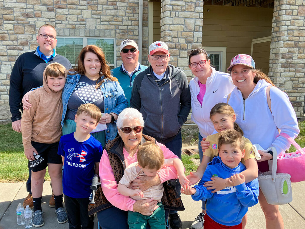 Celebrating a wonderful day, a family of a senior resident strikes a pose outside. Happiness radiates from their faces as they create lasting memories in a group photo.